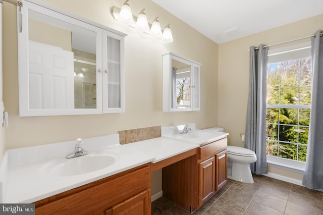 bathroom with a sink, toilet, a stall shower, and double vanity