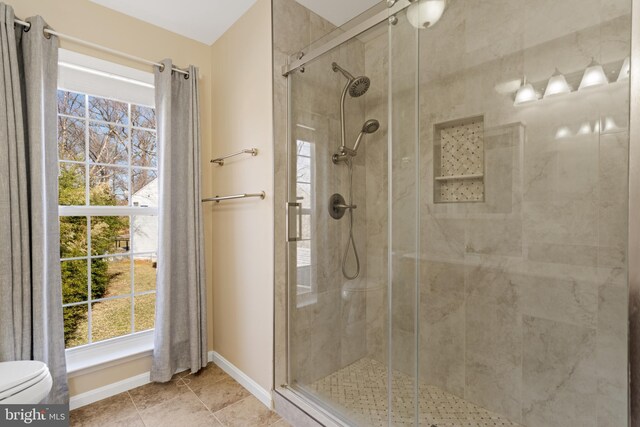 full bathroom with baseboards, toilet, a stall shower, and tile patterned flooring