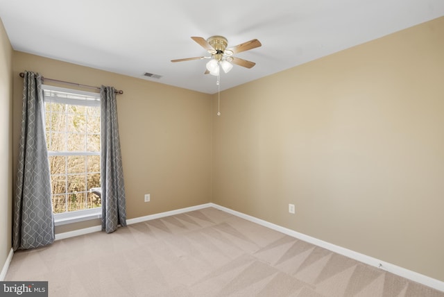 spare room featuring visible vents, light colored carpet, baseboards, and a healthy amount of sunlight