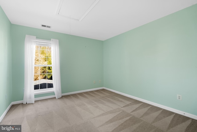 empty room featuring baseboards, visible vents, attic access, and carpet