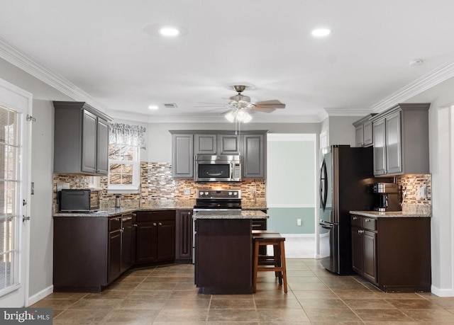 kitchen featuring light stone counters, visible vents, a kitchen island, and appliances with stainless steel finishes