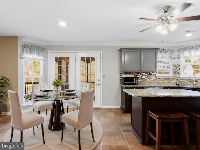 dining area with visible vents, a ceiling fan, crown molding, a toaster, and baseboards