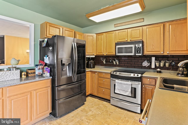 kitchen featuring stainless steel appliances, tasteful backsplash, light countertops, light brown cabinets, and a sink