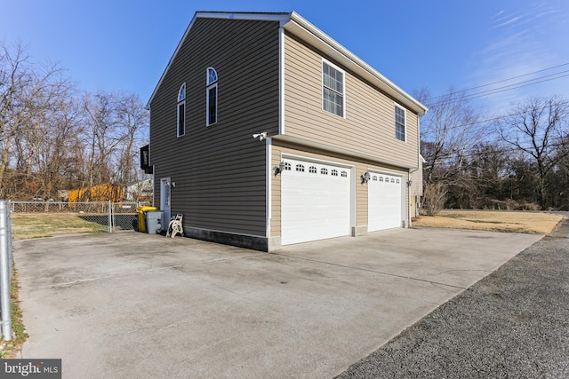 view of home's exterior featuring driveway, an attached garage, and fence