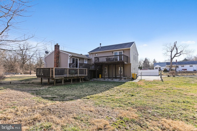 back of property with a yard, a wooden deck, and fence