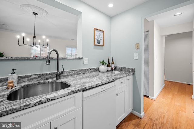 kitchen with dishwasher, light wood-style flooring, light stone counters, white cabinetry, and a sink