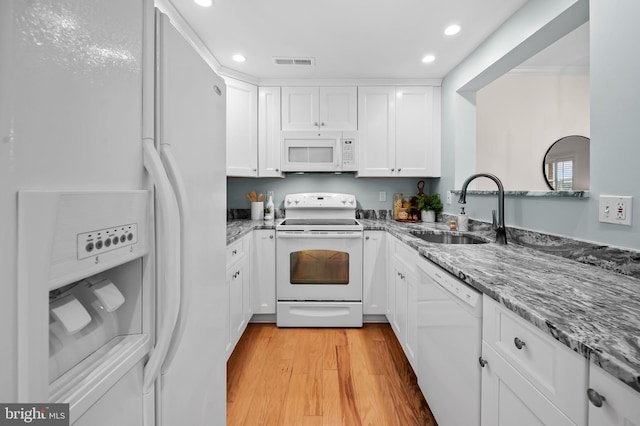 kitchen with white appliances, visible vents, white cabinets, light wood-style flooring, and a sink