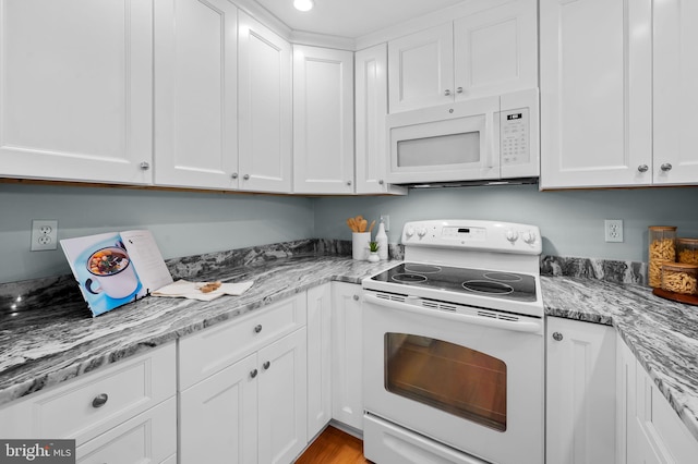 kitchen with white appliances, white cabinetry, and light stone countertops