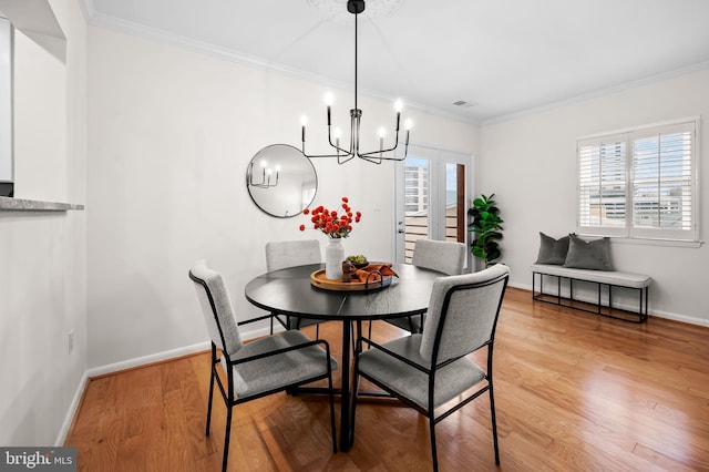 dining area with light wood-style flooring, crown molding, visible vents, baseboards, and an inviting chandelier