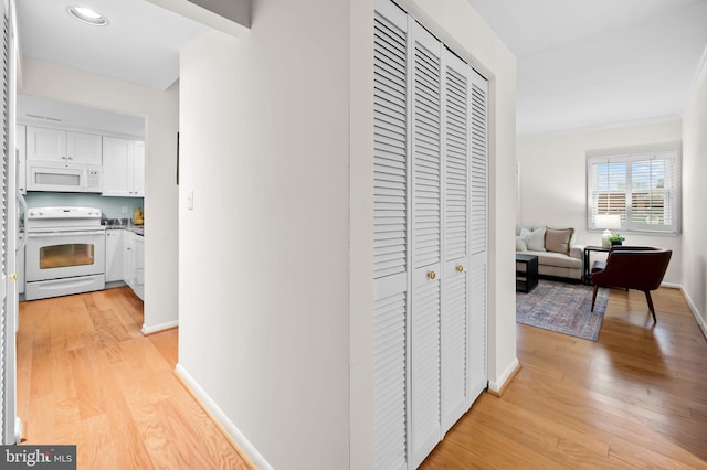 hallway featuring light wood-type flooring and baseboards