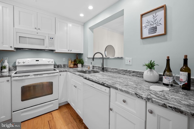 kitchen featuring white appliances, light stone countertops, light wood-type flooring, white cabinetry, and a sink