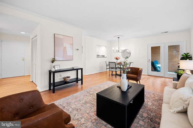 living room with baseboards, wood finished floors, an inviting chandelier, crown molding, and french doors