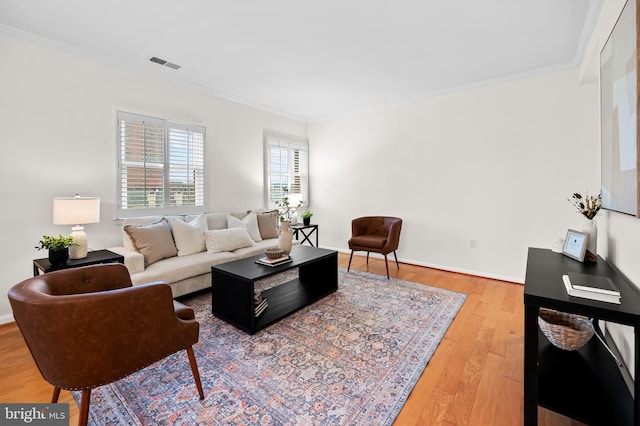 living area featuring ornamental molding, visible vents, baseboards, and wood finished floors