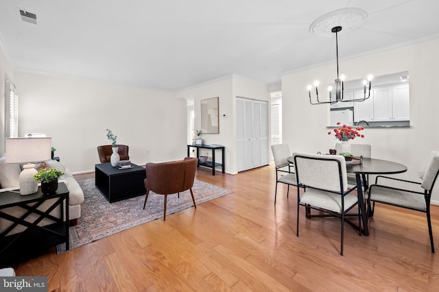 dining room featuring light wood-style flooring, crown molding, visible vents, and a notable chandelier