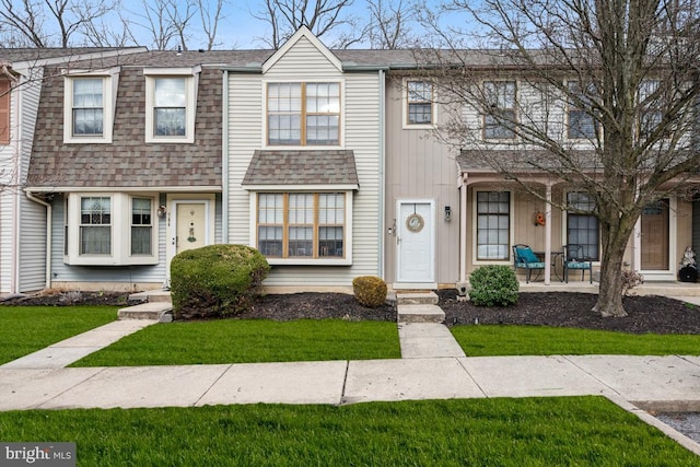 multi unit property featuring covered porch, a front lawn, and roof with shingles