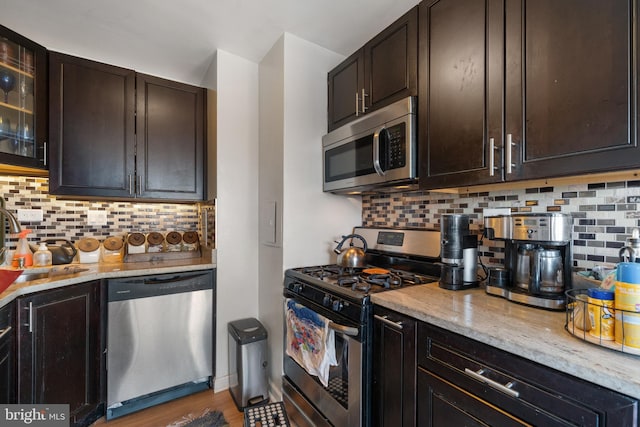 kitchen with light stone counters, stainless steel appliances, tasteful backsplash, and dark brown cabinetry