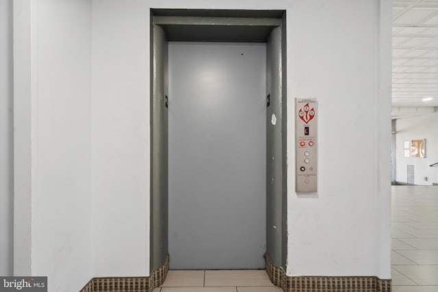 hallway with elevator and light tile patterned floors