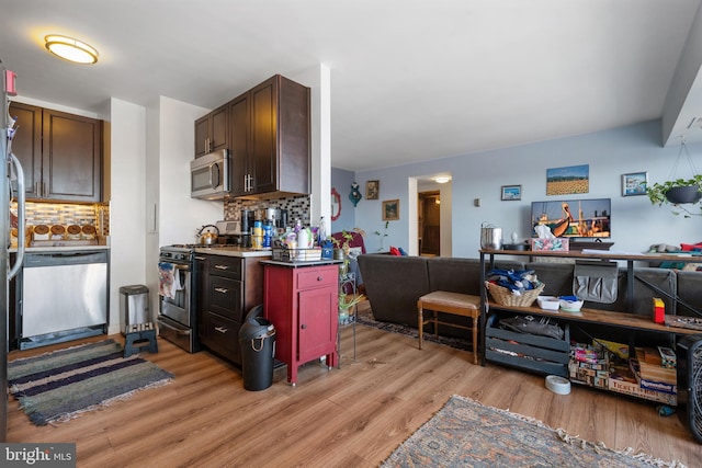 kitchen featuring stainless steel appliances, tasteful backsplash, open floor plan, and light wood-style flooring