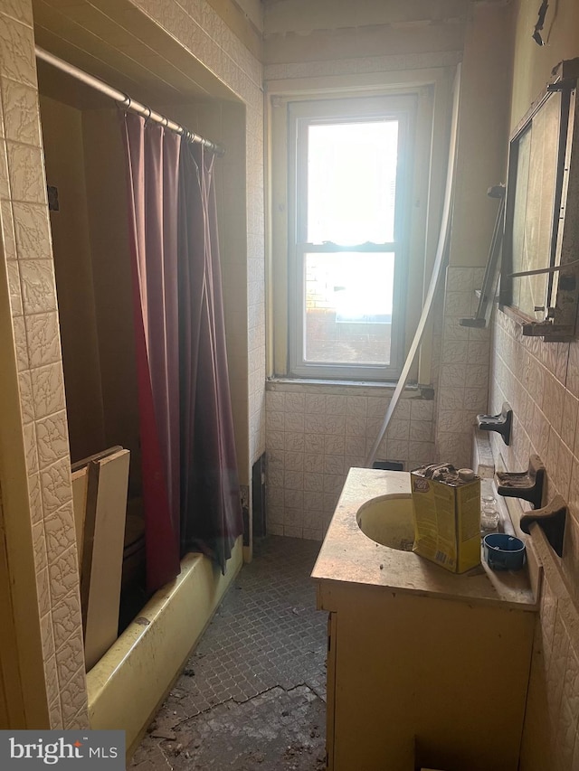 full bath with curtained shower, vanity, and tile walls