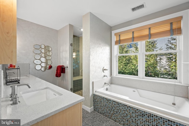 bathroom featuring double vanity, visible vents, a garden tub, a shower stall, and a sink