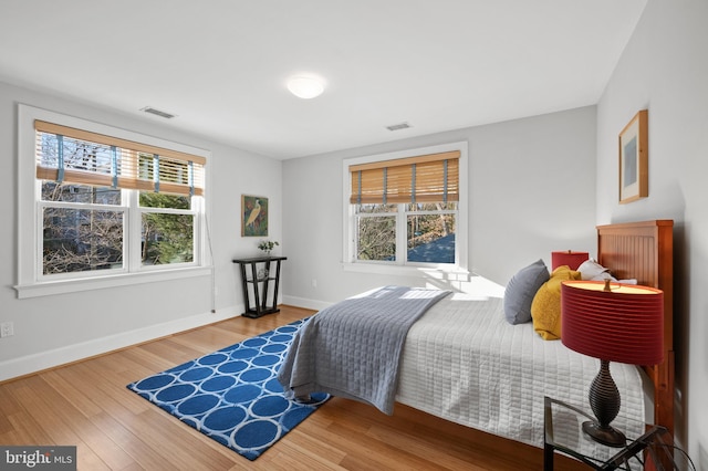 bedroom with multiple windows, visible vents, and wood finished floors