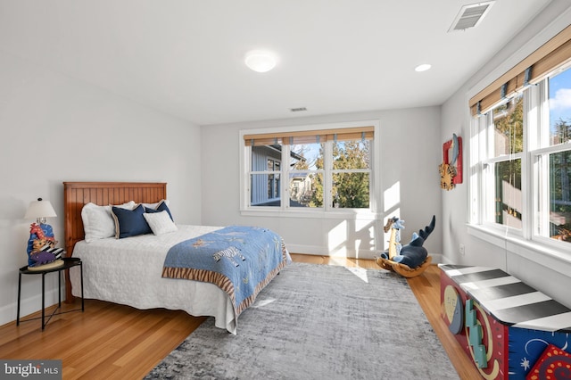 bedroom with recessed lighting, wood finished floors, visible vents, and baseboards