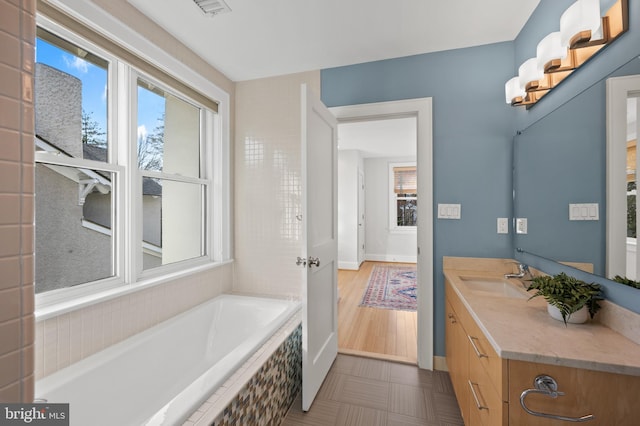 full bathroom featuring visible vents, a garden tub, vanity, and baseboards