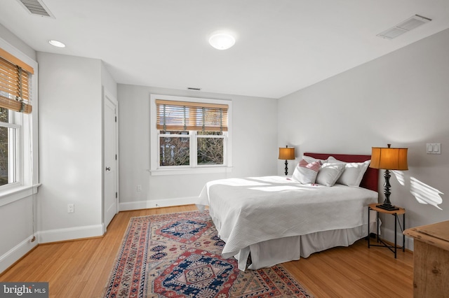 bedroom with light wood-style flooring, visible vents, and baseboards