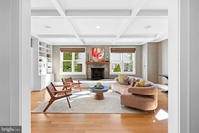 living area featuring a fireplace with raised hearth, recessed lighting, coffered ceiling, beam ceiling, and light wood finished floors