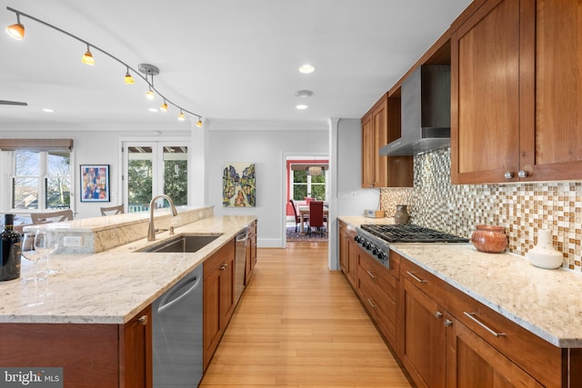 kitchen featuring ornamental molding, wall chimney exhaust hood, appliances with stainless steel finishes, and a sink