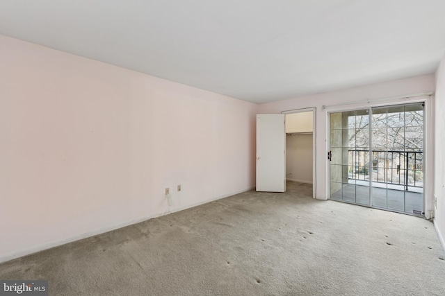 unfurnished bedroom featuring access to exterior, a closet, carpet flooring, and a spacious closet