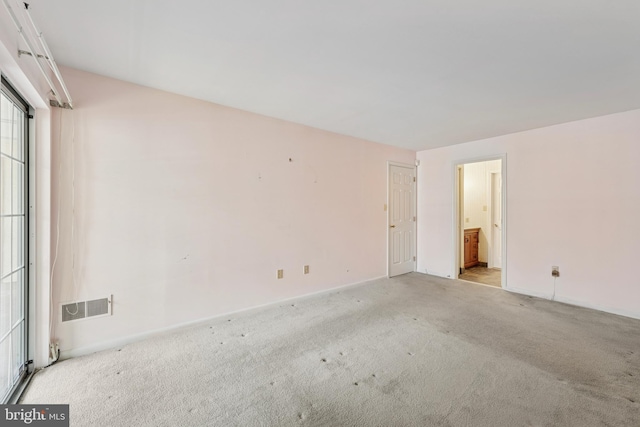 unfurnished bedroom with carpet floors, baseboards, visible vents, and ensuite bath