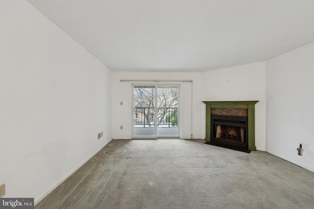 unfurnished living room with carpet floors, visible vents, baseboards, and a premium fireplace