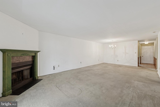 unfurnished living room with a tiled fireplace, carpet flooring, and an inviting chandelier