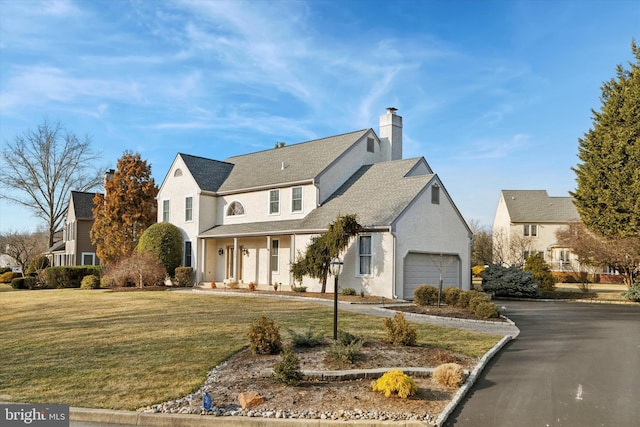 traditional home featuring a garage, driveway, a chimney, and a front lawn