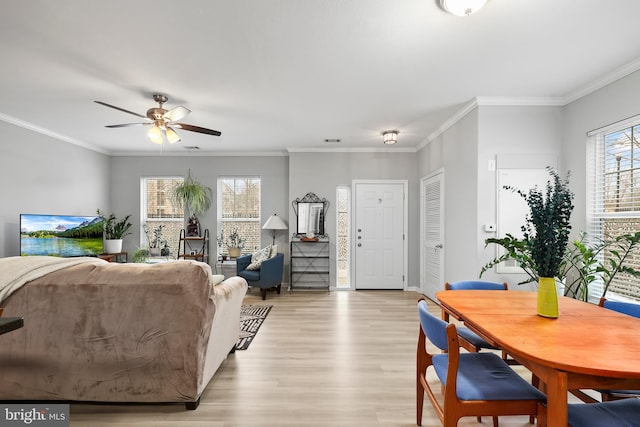 living area featuring visible vents, a ceiling fan, baseboards, ornamental molding, and light wood-type flooring