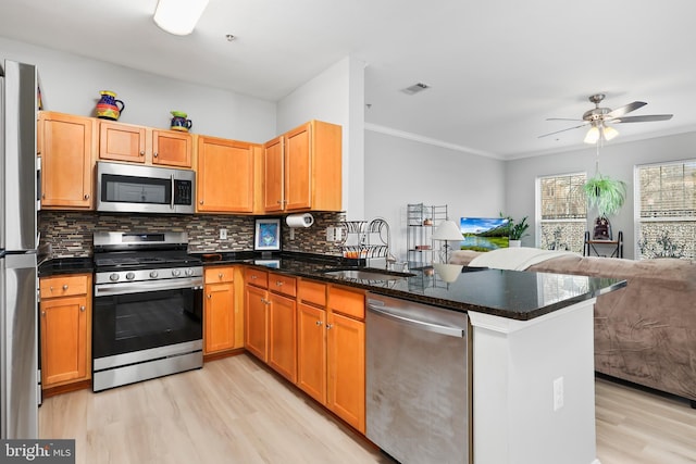 kitchen with a sink, visible vents, open floor plan, appliances with stainless steel finishes, and backsplash