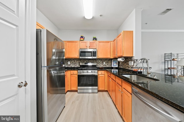 kitchen with visible vents, decorative backsplash, appliances with stainless steel finishes, dark stone countertops, and a sink