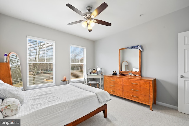 bedroom featuring light carpet, a ceiling fan, and baseboards