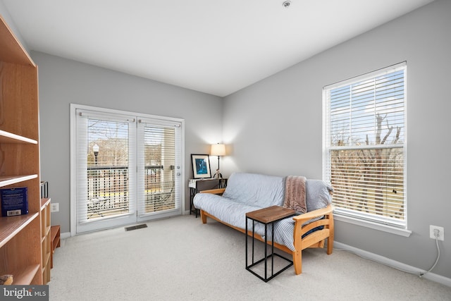 living area with carpet floors, plenty of natural light, visible vents, and baseboards