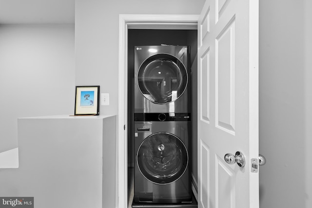 clothes washing area with stacked washer / dryer and laundry area