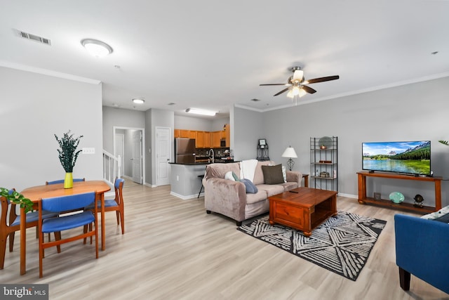 living room with baseboards, visible vents, a ceiling fan, light wood-style flooring, and crown molding