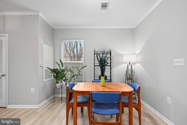 dining room featuring ornamental molding, visible vents, light wood-style flooring, and baseboards