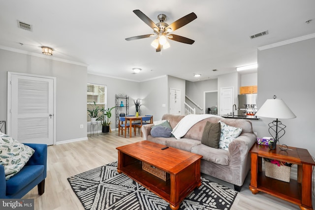 living area featuring light wood finished floors, visible vents, and crown molding