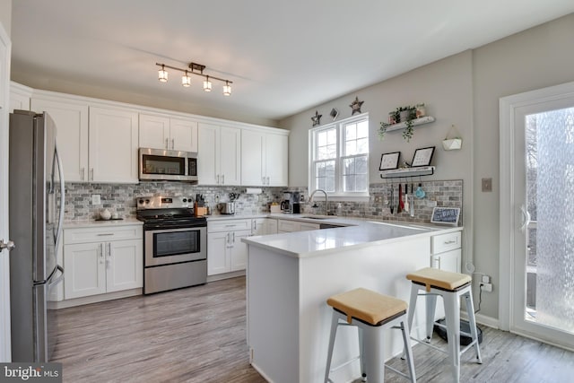 kitchen featuring white cabinetry, a kitchen bar, appliances with stainless steel finishes, and decorative backsplash