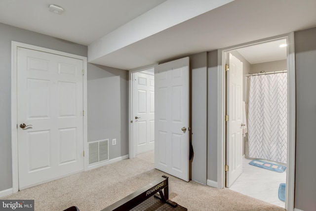 interior space with visible vents, light carpet, baseboards, and ensuite bathroom