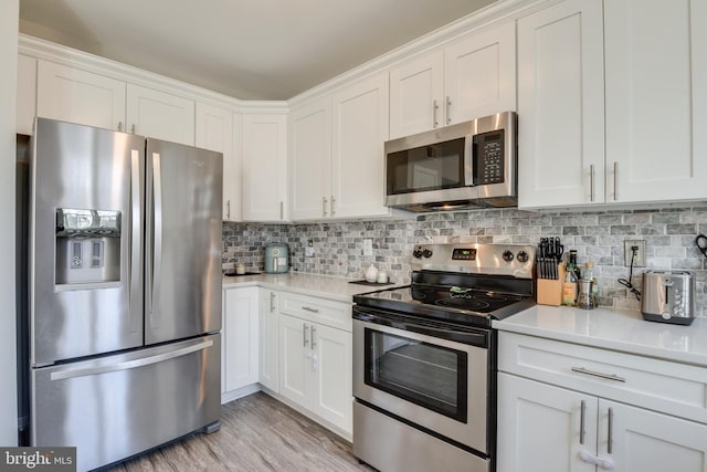 kitchen featuring appliances with stainless steel finishes, white cabinets, light countertops, and decorative backsplash