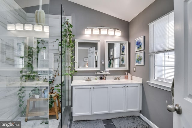 bathroom featuring lofted ceiling, double vanity, a shower, and a sink