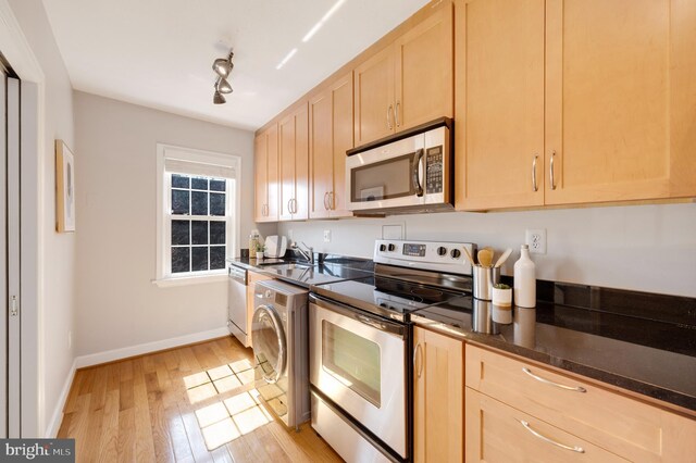 kitchen with light brown cabinets, baseboards, washer / dryer, appliances with stainless steel finishes, and light wood-type flooring