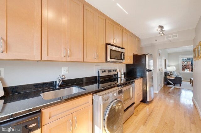 kitchen with visible vents, light brown cabinets, a sink, stainless steel appliances, and washer / dryer